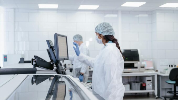Innovation hospitalière Un scientifique en tenue de protection utilise un équipement dans un laboratoire moderne.