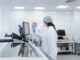 Un scientifique en tenue de protection utilise un équipement dans un laboratoire moderne.